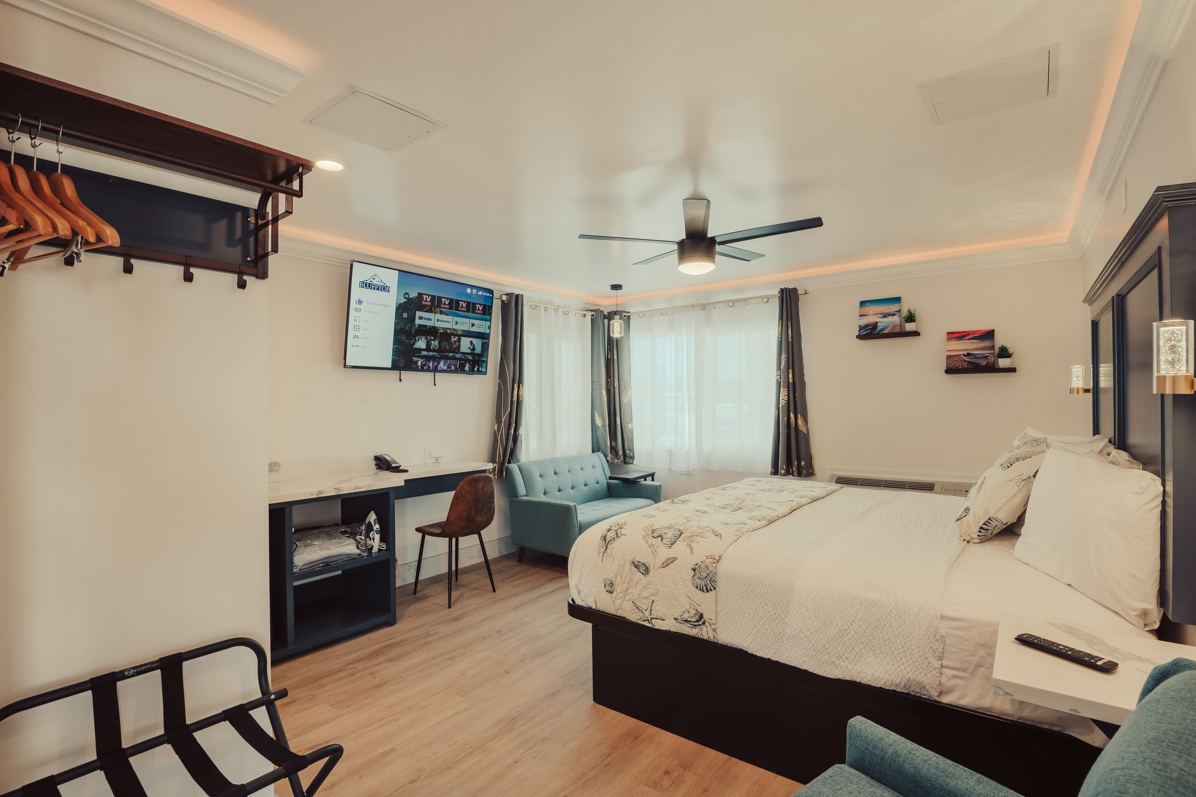A hotel room with a bed, desk, chair, and a ceiling fan.