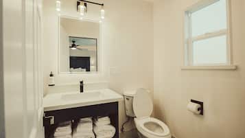 A bathroom with a white sink, a mirror, a toilet, and a towel rack.