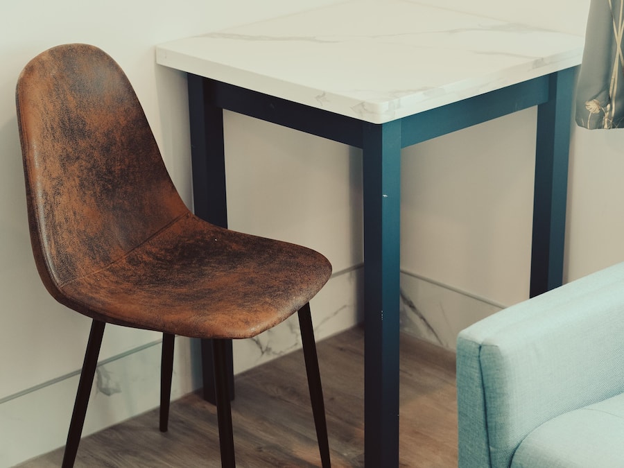 A room with a wooden chair, a table with a marble top, and a blue sofa.