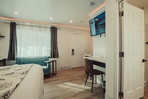 A hotel room with a bed, a desk, a chair, a TV, and a window with curtains. - Blufftop Inn & Suites - Wharf/Restaurant District (Morro Bay)