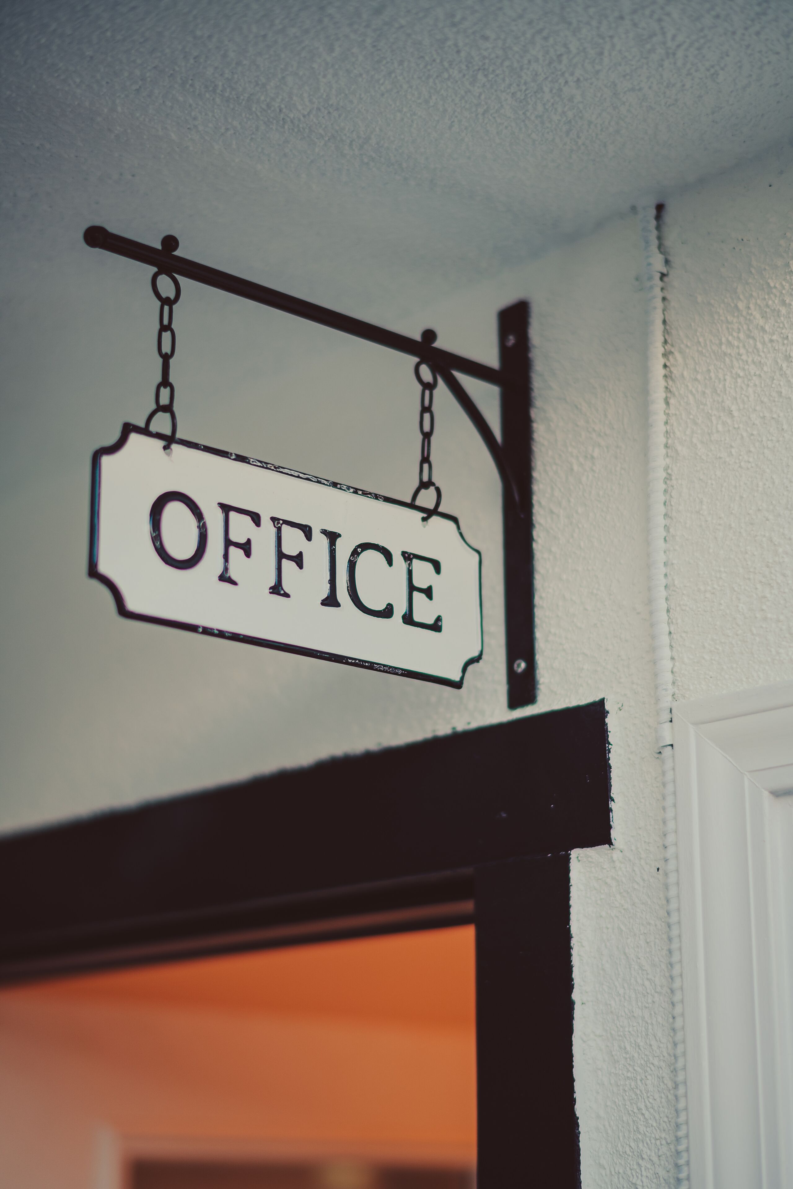 A sign hanging from a ceiling that reads "OFFICE."