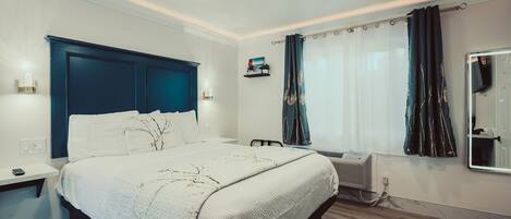 A bedroom with a bed, bedside tables, a ceiling fan, a window with curtains, and a wall-mounted shelf.