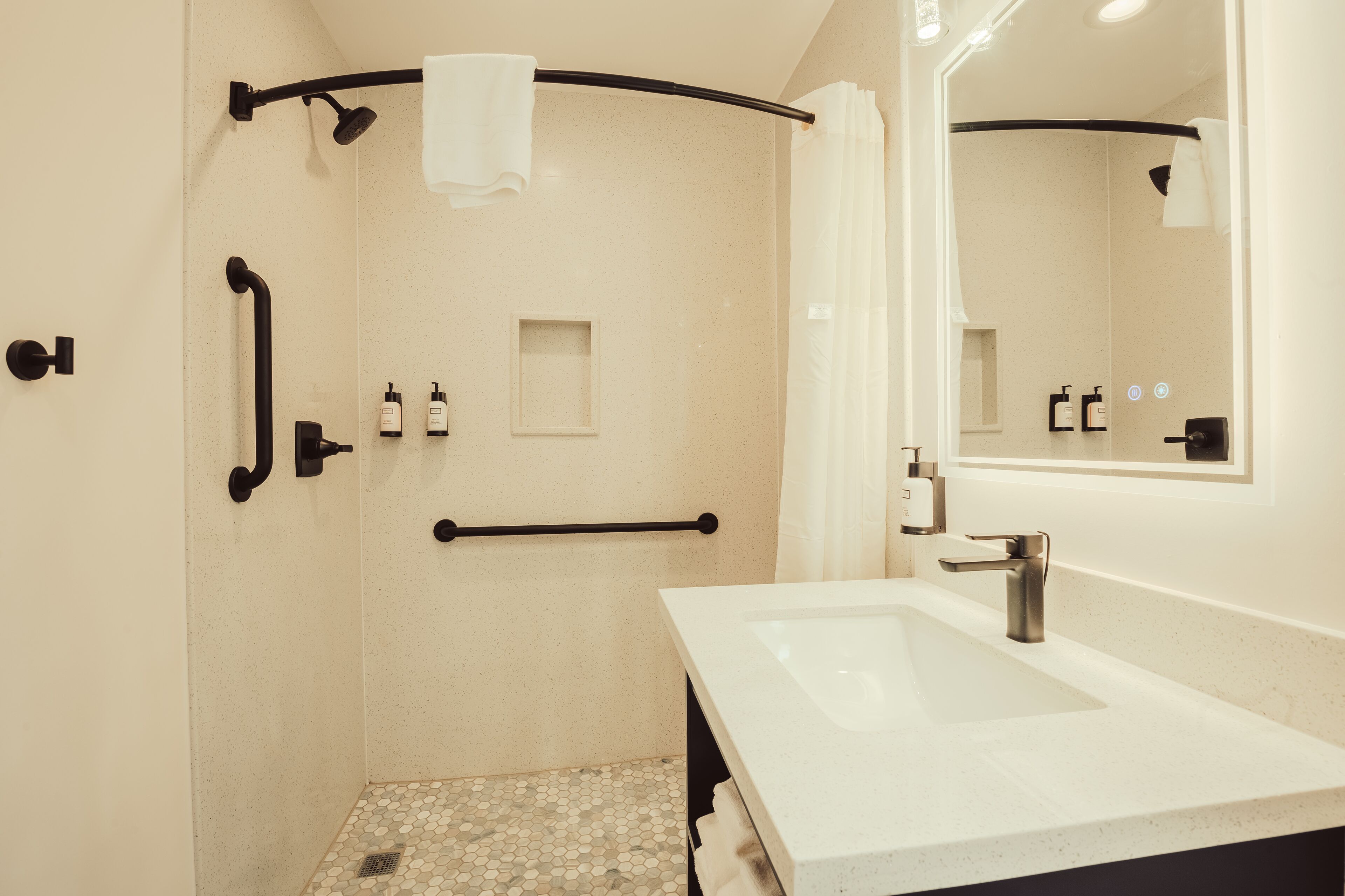 A modern bathroom with a shower, a sink, and a mirror.
