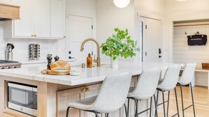 A modern kitchen with white cabinetry, a central island with bar stools, and pendant lighting.