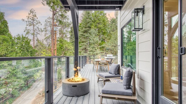 A deck with a fire pit, seating, and a view of the forest.