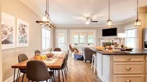 A spacious kitchen with a dining area, wooden flooring, and pendant lighting. - Covered Deck + Firepit | Black Mountain Retreat | Sweetgum by AvantStay (Black Mountain)