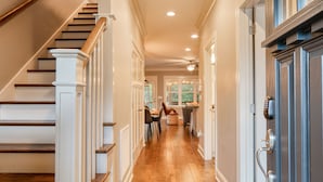 A hallway with wooden stairs, white walls, and a door with a keypad lock. - Covered Deck + Firepit | Black Mountain Retreat | Sweetgum by AvantStay (Black Mountain)