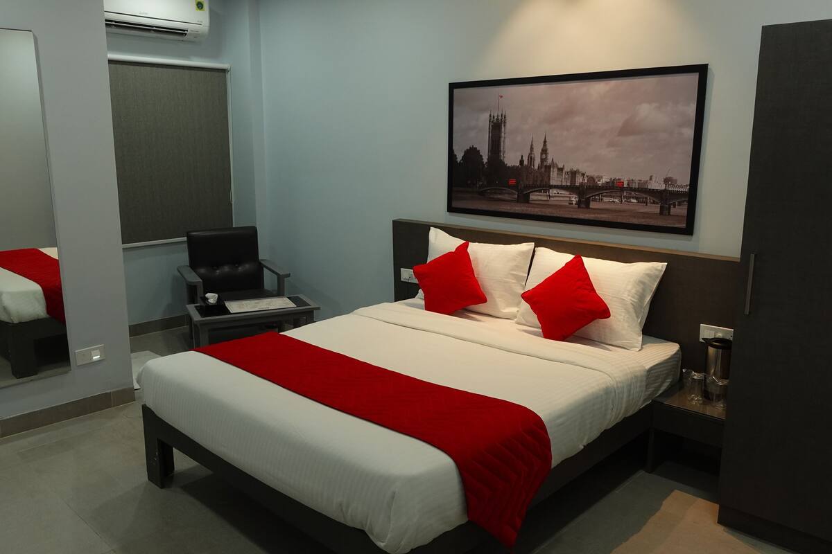 Ein Hotelzimmer mit einem Bett, einem Sessel, einem Schreibtisch, einem Spiegel und einem Stadtbild.