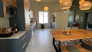 A modern kitchen with a wooden dining table, hanging pendant lights, and a microwave. - Comfortable (122m2) 1.2km from the beach (Jard-sur-Mer)