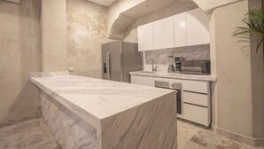 Una cocina moderna con una isla de mármol, electrodomésticos de acero inoxidable y armarios blancos.