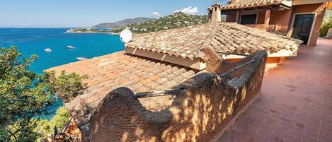 A coastal property with a tiled roof, a stone wall, and a view of the sea.