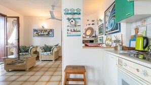 Ein gemütliches Wohnzimmer mit einem Rattan-Sofa, einem Holzschemel und einem Fliesenboden.