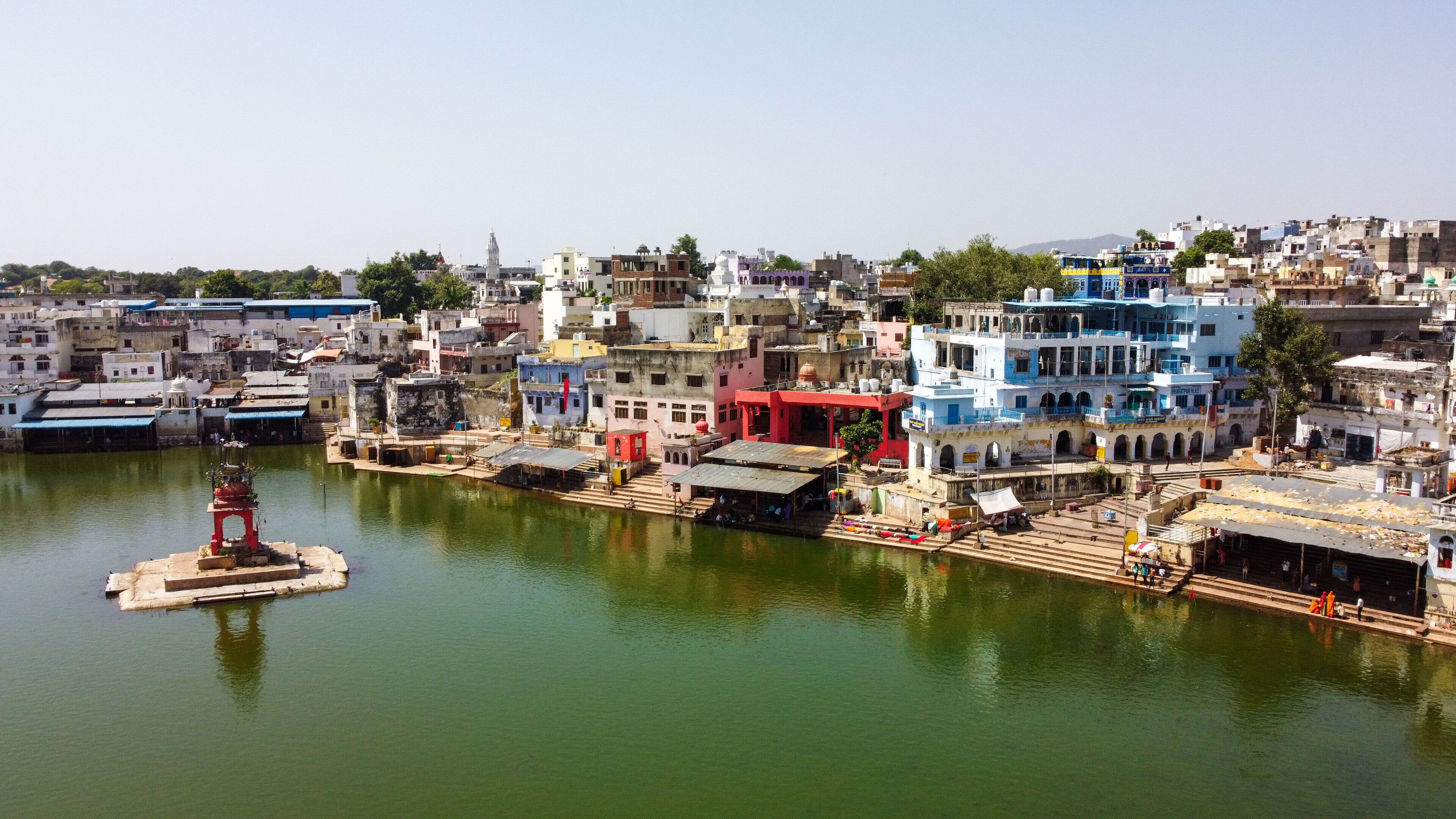 A riverside view of a densely packed urban area with buildings of various architectural styles, including some with domes and arches.