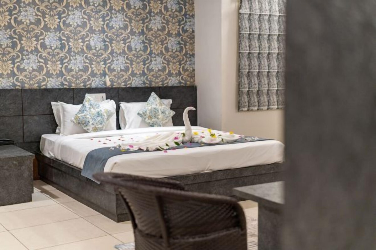 Ein ordentlich gemachtes Bett mit floralen Kissen, einem schwanenförmigen Kopfkissen und einer Schwaneinrichtung auf der Bettdecke.