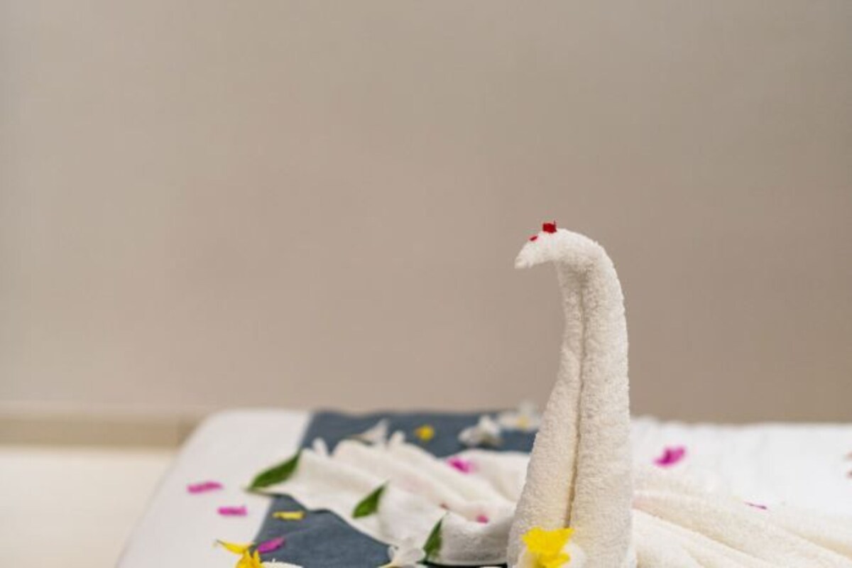 A white swan-shaped object on a bed with a floral-patterned bedspread.