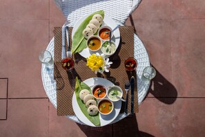 A table set with a meal consisting of idlis, sambar, and coconut chutney, accompanied by a yellow flower. - Vesta Avtar Resort Pushkar (Pushkar)