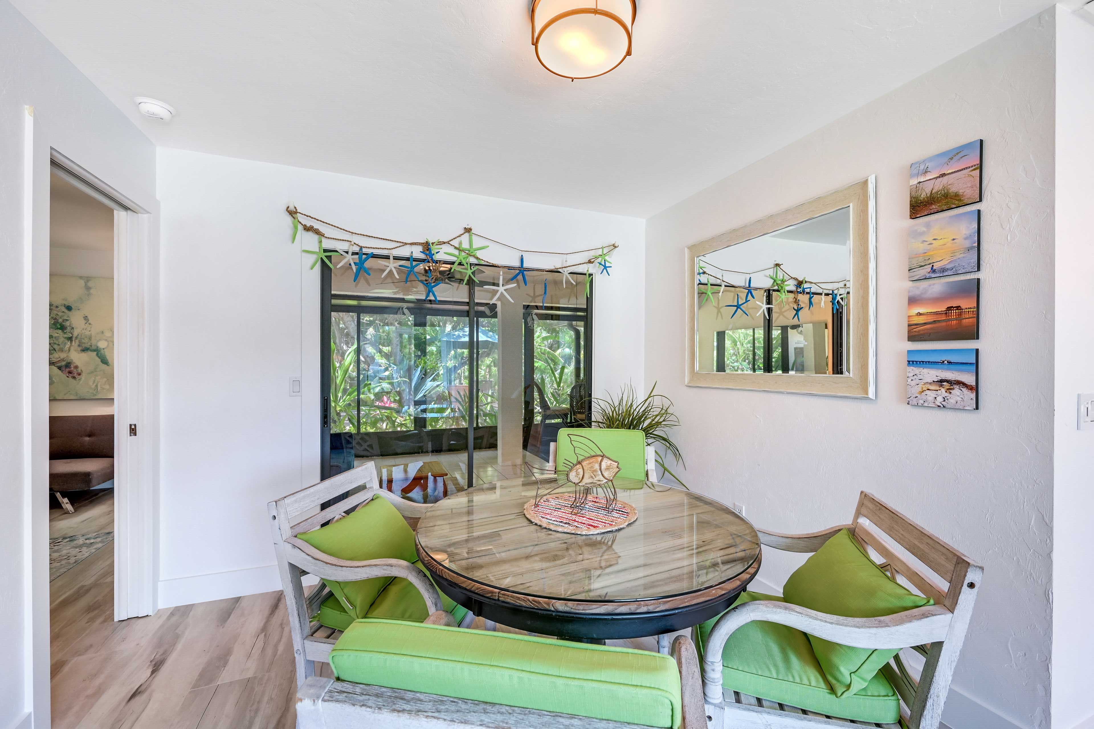 A dining area with a round table, chairs, and a view through glass doors.