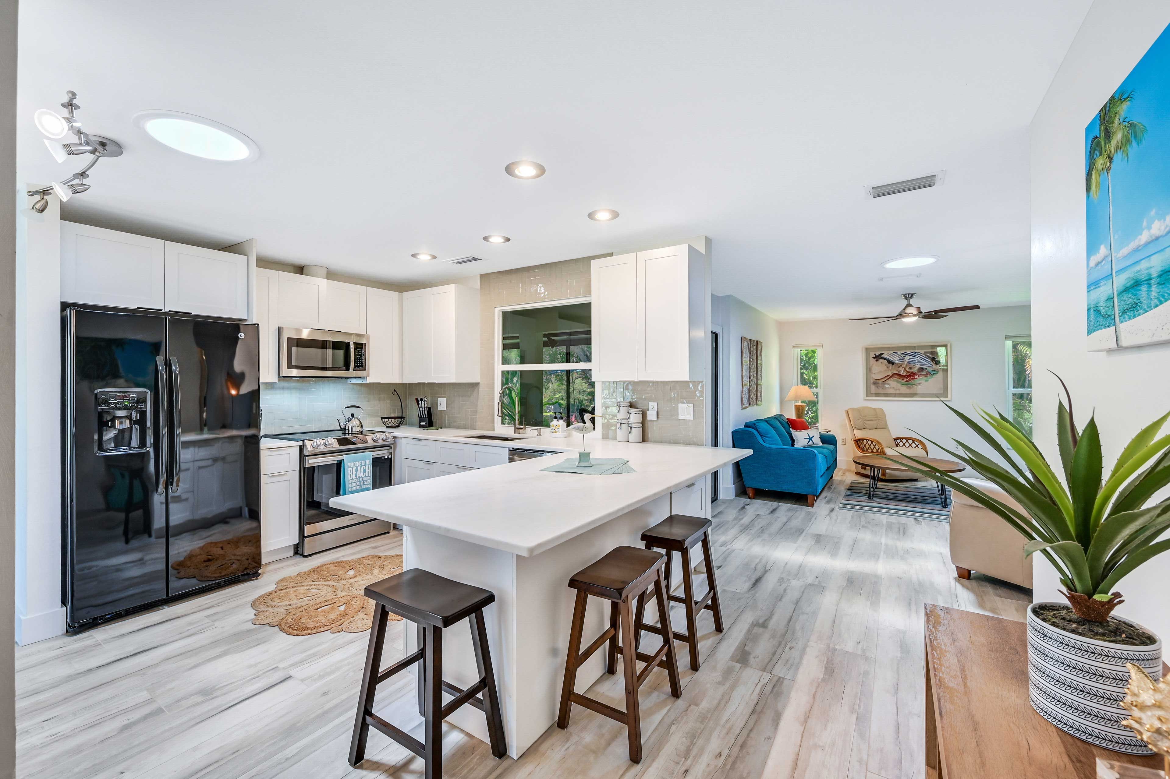 A modern kitchen with a central island, stainless steel appliances, and a dining area with bar stools.