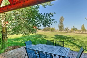 A patio with a table and chairs, surrounded by a grassy lawn and trees. - Serene Driggs Cabin ~ 10 Mi to Grand Targhee! (Driggs)