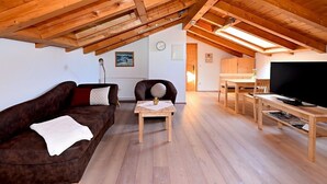 Un salon chaleureux avec un canapé marron, une petite table en bois et un téléviseur.