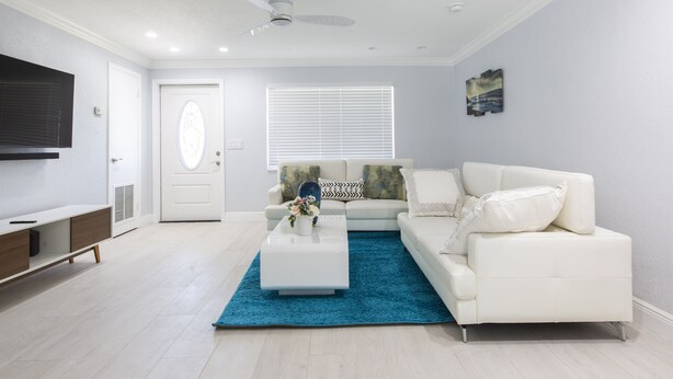 A modern living room with a white sofa, a coffee table, and a blue rug.