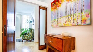 A wooden desk with a bowl, a colorful painting, and a chair in a well-lit hallway. - Amazing Villa El Sueno 3 (Puerto Vallarta)