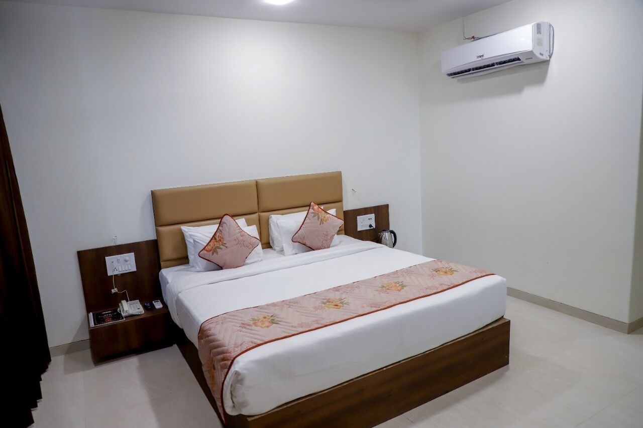 Una cama bien hecha con cabecera de madera, una mesita de noche con un teléfono y un equipo de aire acondicionado instalado en la pared.