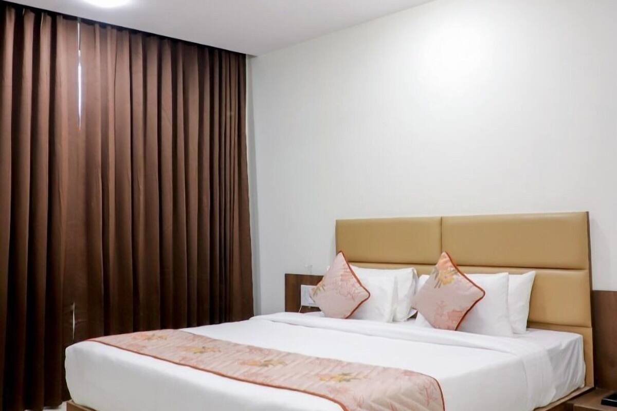 Ein Hotelzimmer mit Bett, Vorhängen, Deckenventilator und Einbaustrahlern.