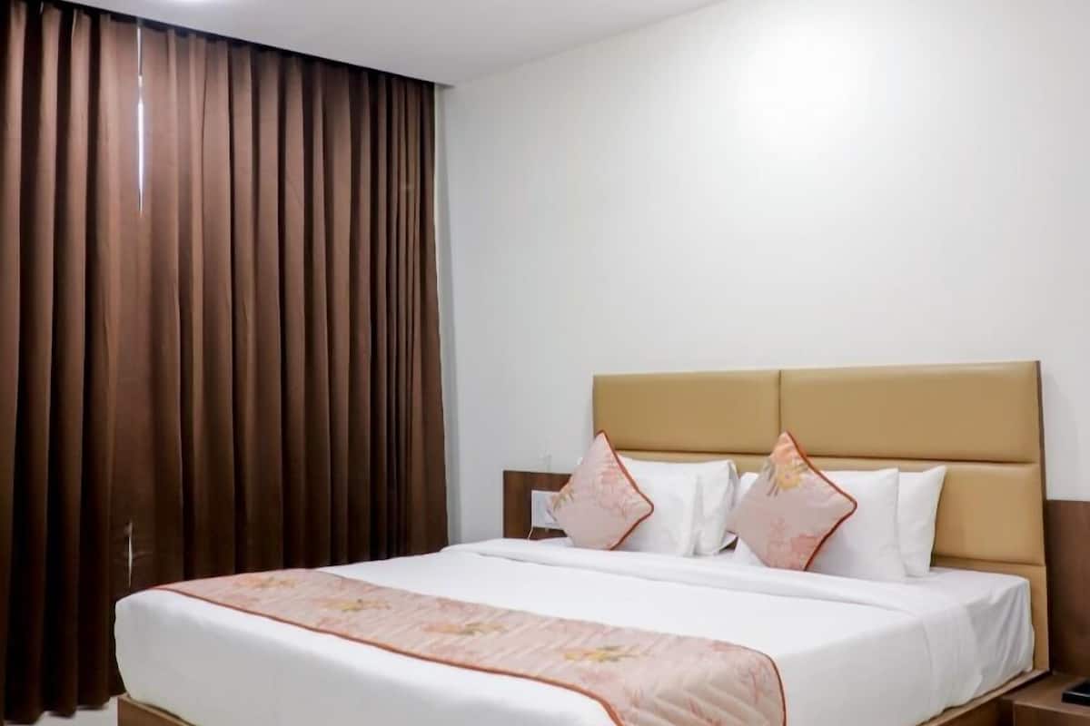 Ein Hotelzimmer mit einem großen Bett, einem Deckenventilator und einem Fenster mit Vorhängen.