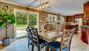Een moderne keuken met een centraal eiland, een zithoek met vier stoelen en een grote potplant.