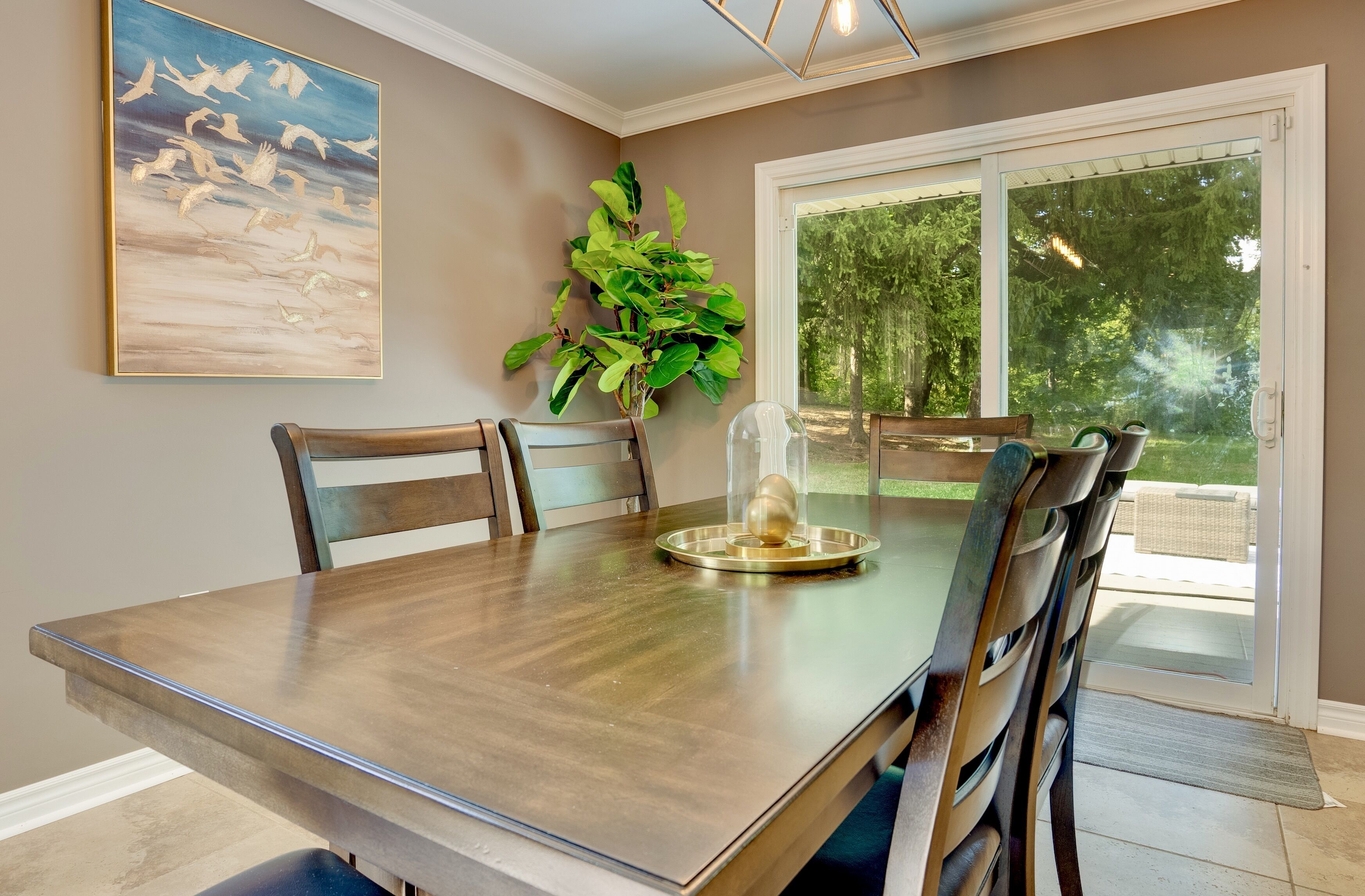A dining area with a wooden table, chairs, a plant, and a glass sculpture.