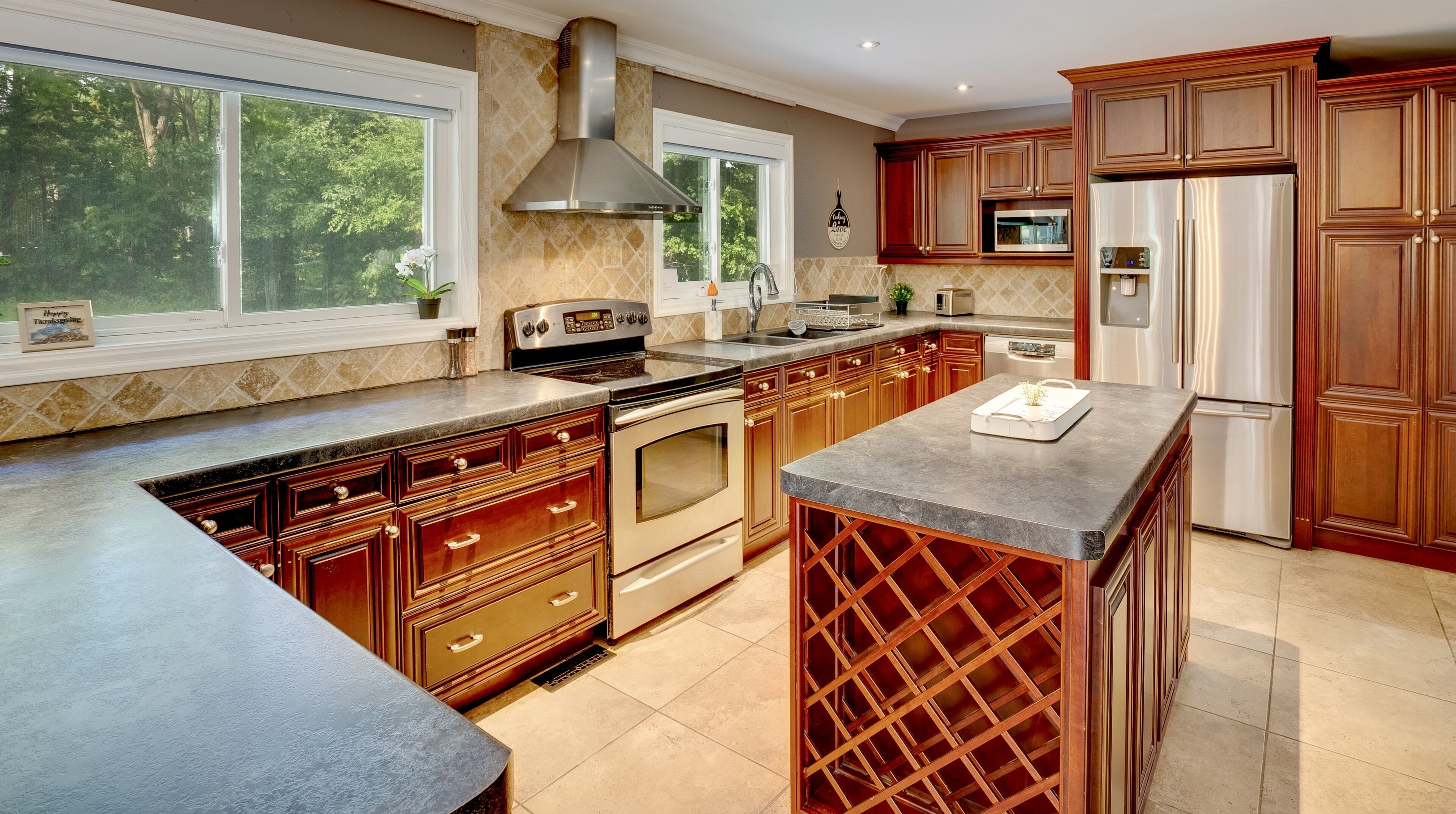 A modern kitchen with a large island, stainless steel appliances, and wooden cabinetry.