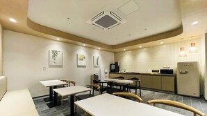 A modern hotel room with a dining area, kitchenette, and artwork on the walls. - Browndot Hotel (Yangsan)