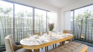 A dining area with a round wooden table set for six, surrounded by chairs and a bench. - The Manor Hoi An Villa (Da Nang)