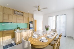 Premier villa | Privékeuken | Een koelkast, een magnetron, een vaatwasser, kookgerei, borden en bestek