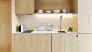 A modern kitchen with wooden cabinetry, a countertop, a sink, a toaster, and a kettle.