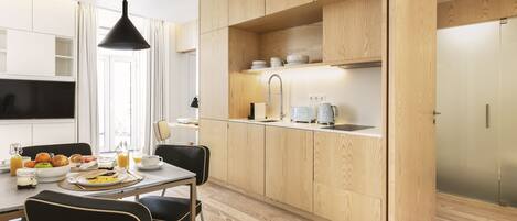 A modern kitchen with wooden cabinets, a dining table with chairs, and a breakfast setup.