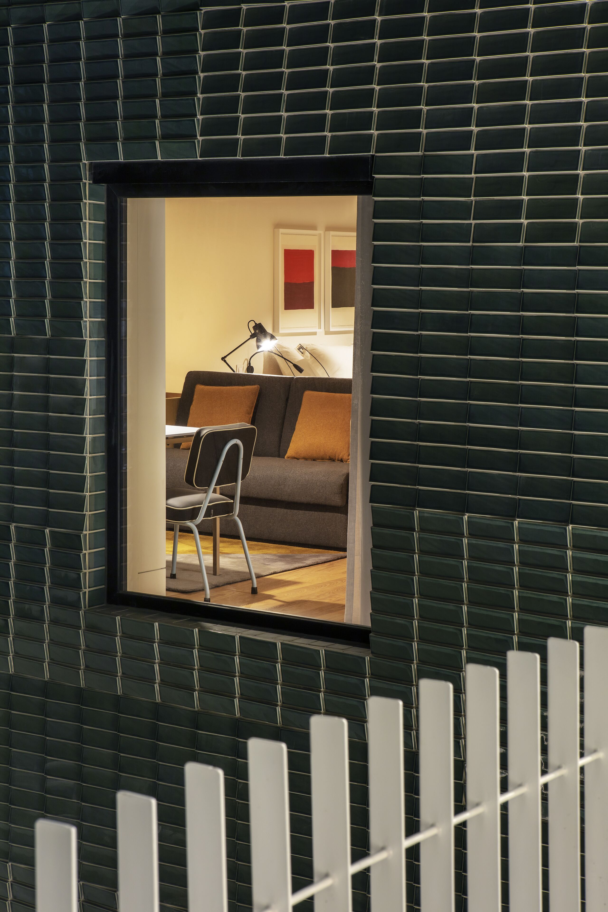 Una habitación con vistas a través de una ventana, un sofá, una silla y una lámpara.