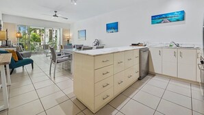 A modern kitchen with a central island, white cabinetry, and artwork on the walls.