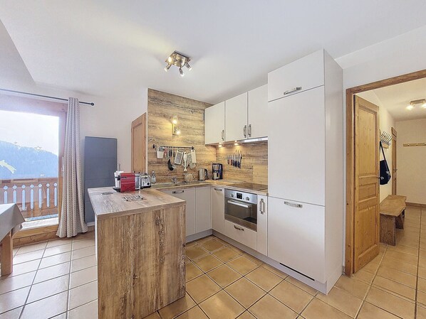Una cocina moderna con armarios blancos, una isla de madera y un horno empotrado.