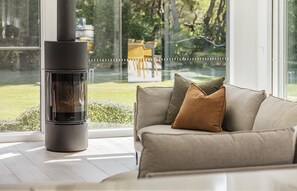 Relax in a spacious living room with a garden view, featuring a wood-burning stove and comfortable seating area.