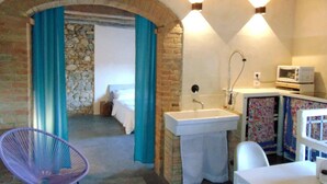 Una habitación con pared de piedra, cama, lavabo y microondas.