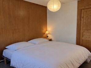 Ein Doppelbett mit weißer Bettwäsche, ein Nachttisch mit Lampe und ein Holzkopfschild.