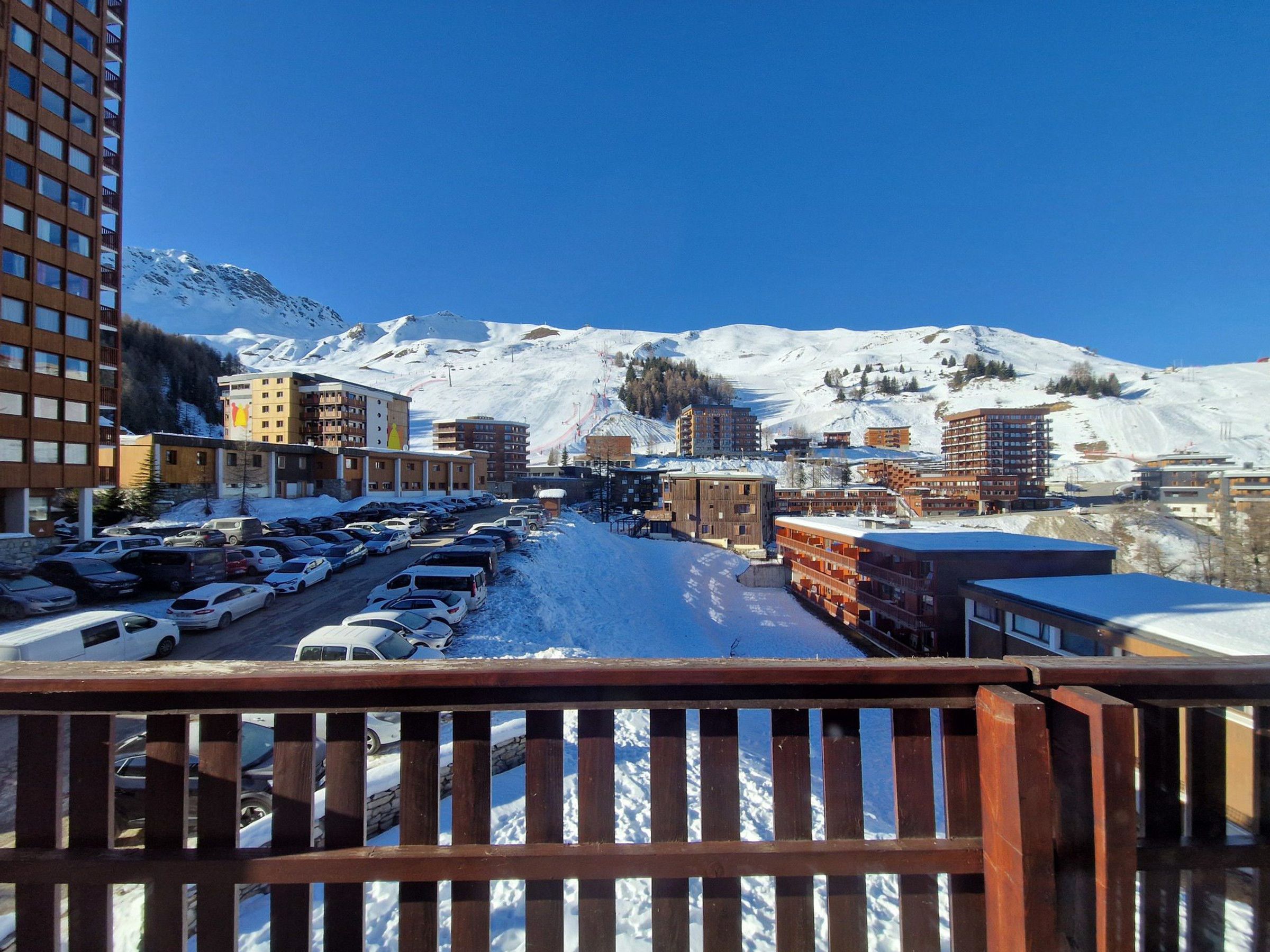 A snowy mountain town with a parking lot and buildings.