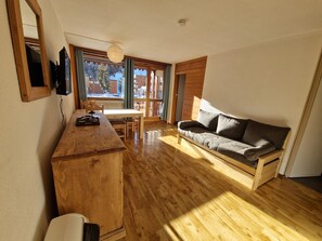 A cozy room with a wooden desk, a sofa, and a television.