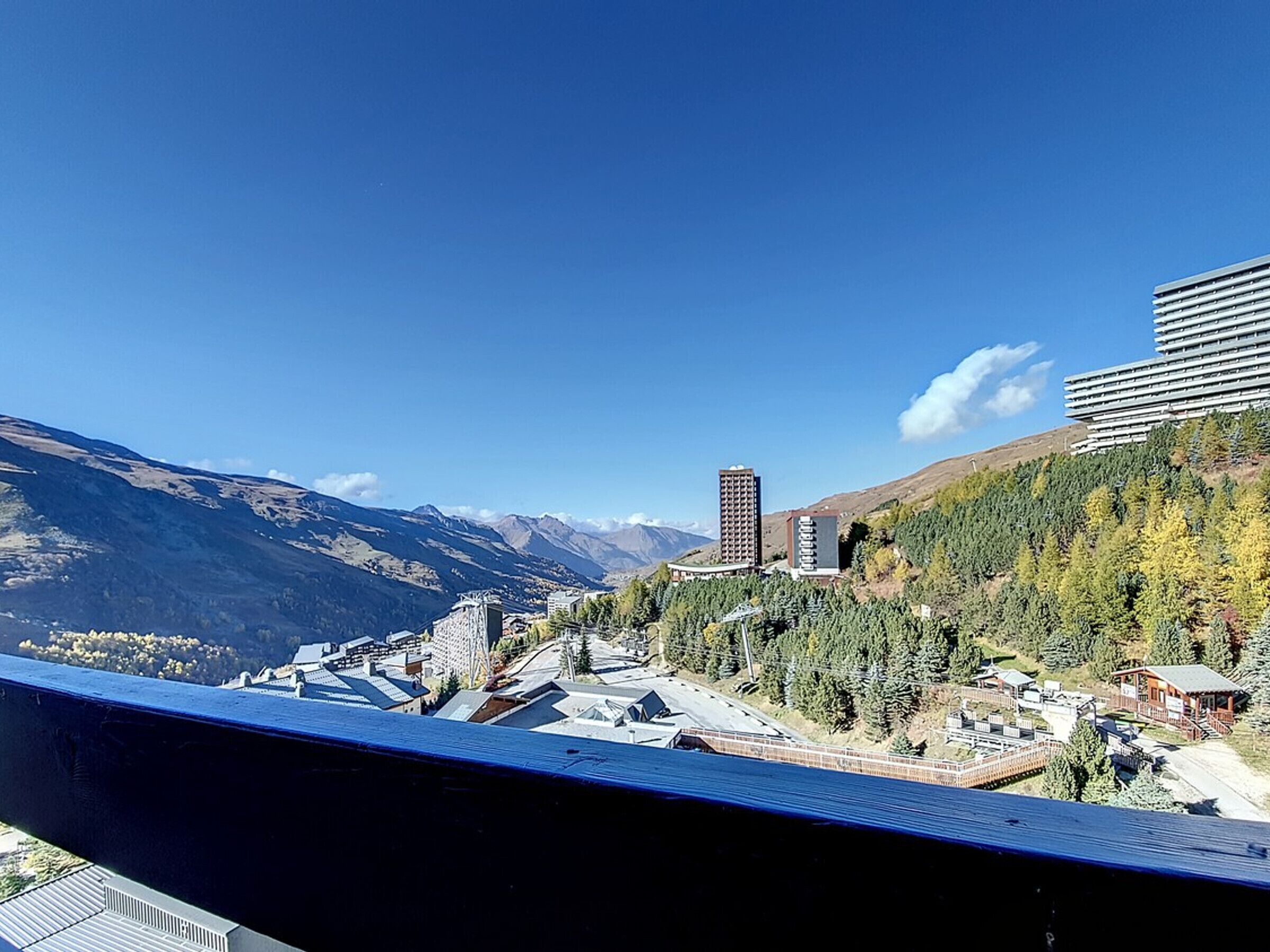 Un paisaje montañoso con edificios, incluyendo una estructura hotelera alta y un edificio más pequeño con techo inclinado.