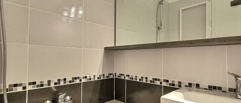 A modern bathroom with a bathtub, a shower, and a vanity with a mirror.
