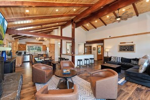 A spacious living room with leather sofas, a coffee table, and a kitchen in the background.