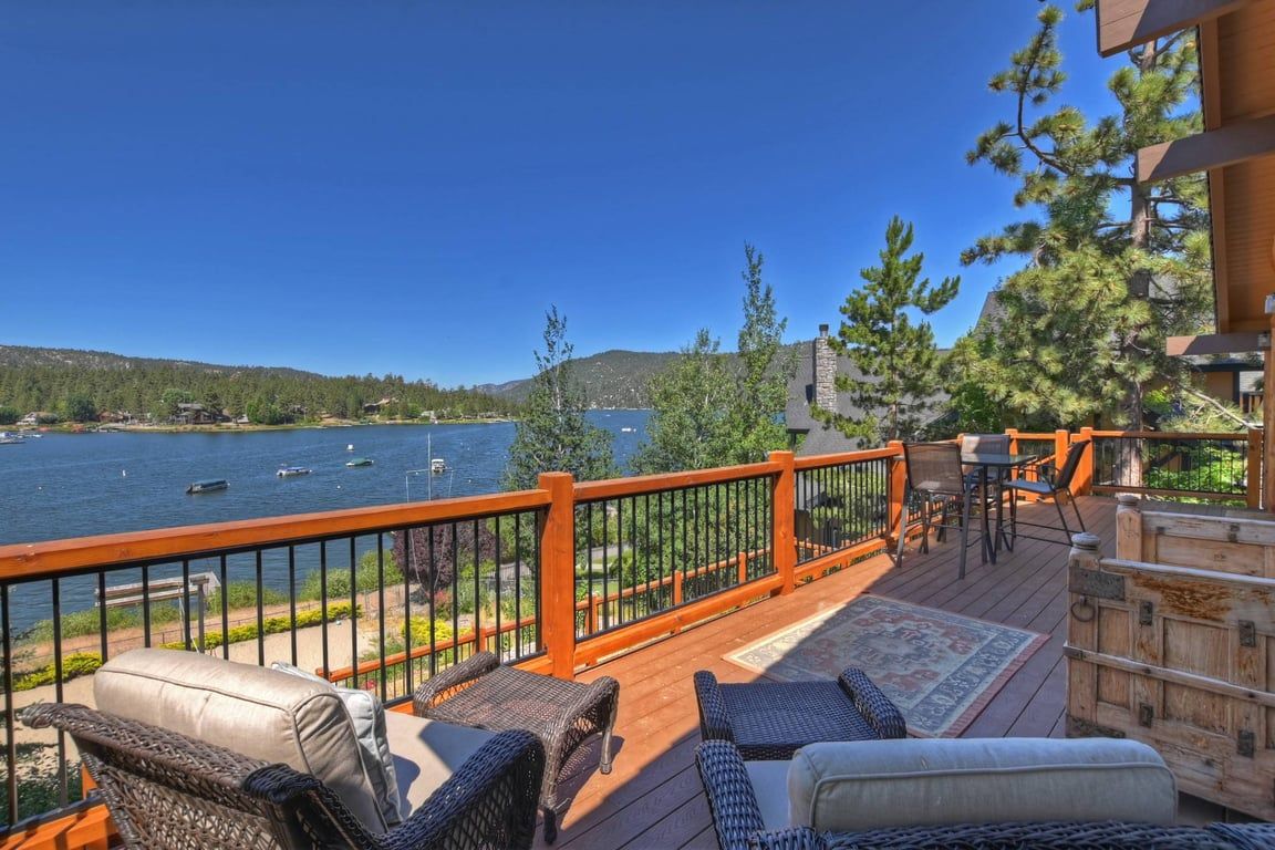 Eine Terrasse mit Gartenmöbeln mit Blick auf einen See mit Booten.