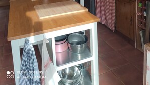 A kitchen with a wooden table, a refrigerator, and a cabinet with glass doors. - Country house on the edge of a forest with landscaped garden. (Billio)